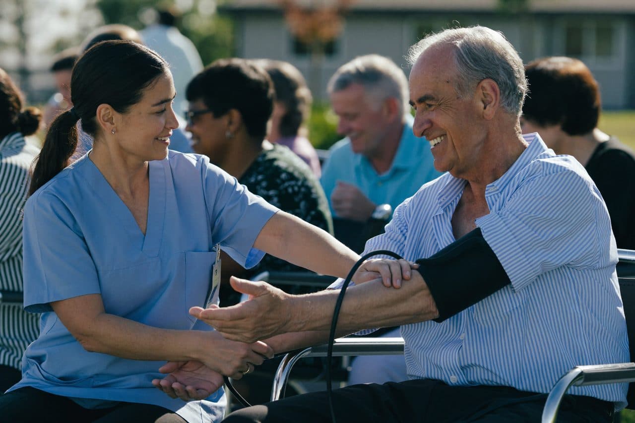 A nurse checking a neighbor's blood pressure at a community wellness event