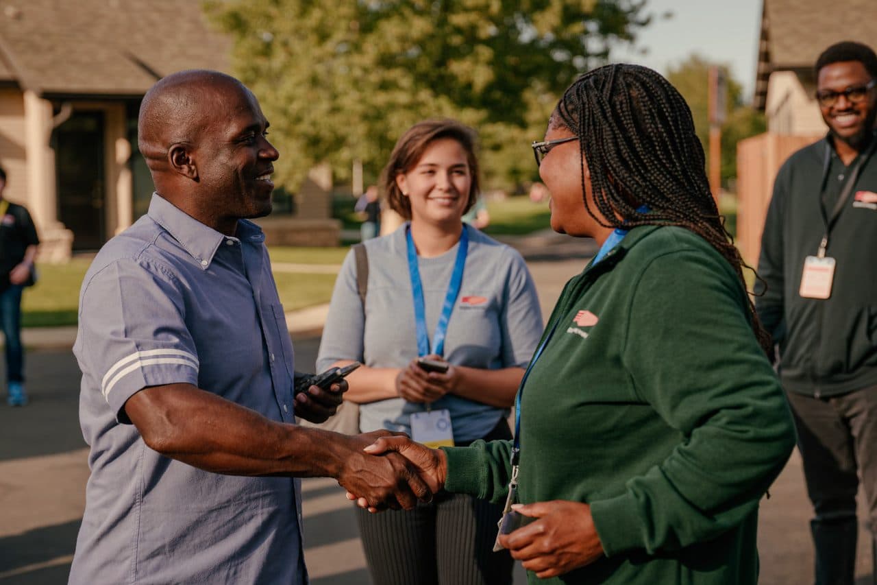 A local business owner and community volunteers shaking hands at an event